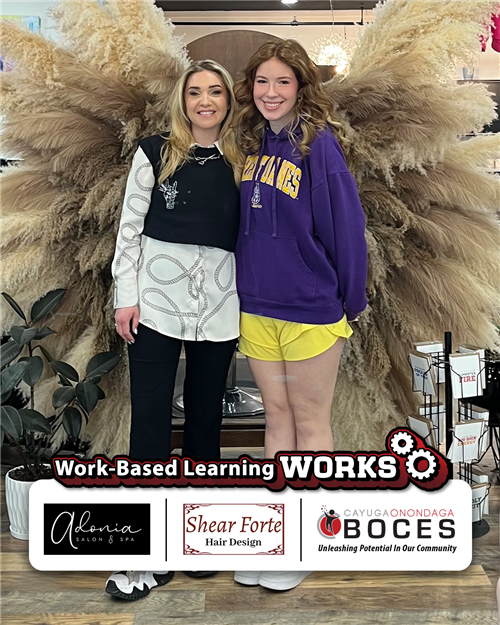 Emme weed posing with her stylist in front of decoration at the salon.